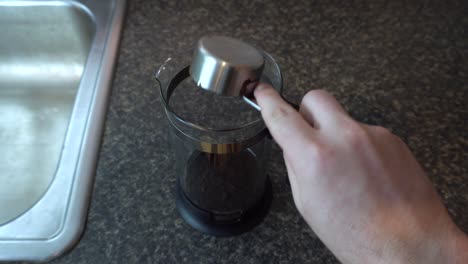 Scooping-coffee-grounds-into-a-french-press-coffee-maker