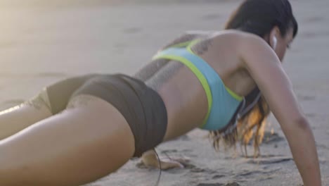 mujer haciendo flexiones en la playa