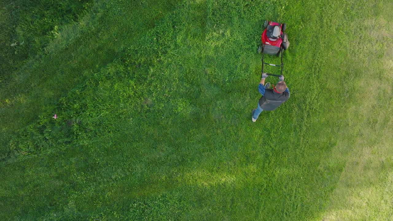 hombre cortando el césped con un cortador de césped rojo