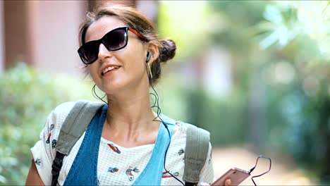 young beautiful woman listening to the music, dancing and singing in the park