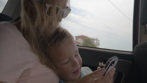 mother and son using mobile phone during car ride