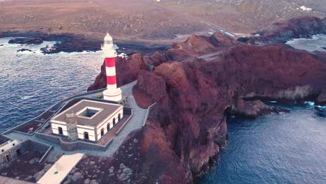 Red-and-white-lighthouse-in-Punta-De-Teno,-Tenerife,-aerial-orbit-view