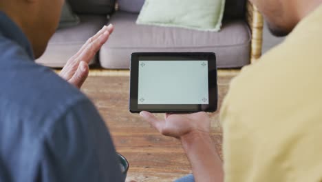 father and son waving hands during video call on digital tablet with blank screen and copy space