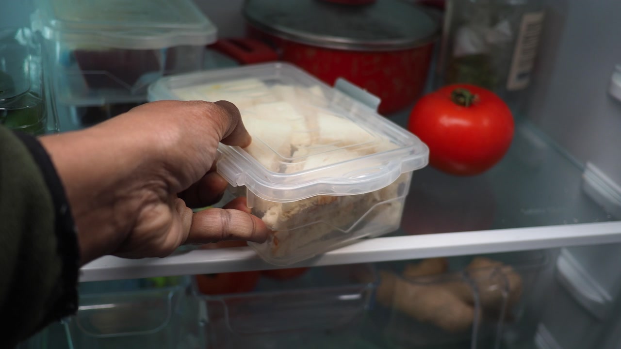 Mano che mette un contenitore di sandwich nel frigorifero