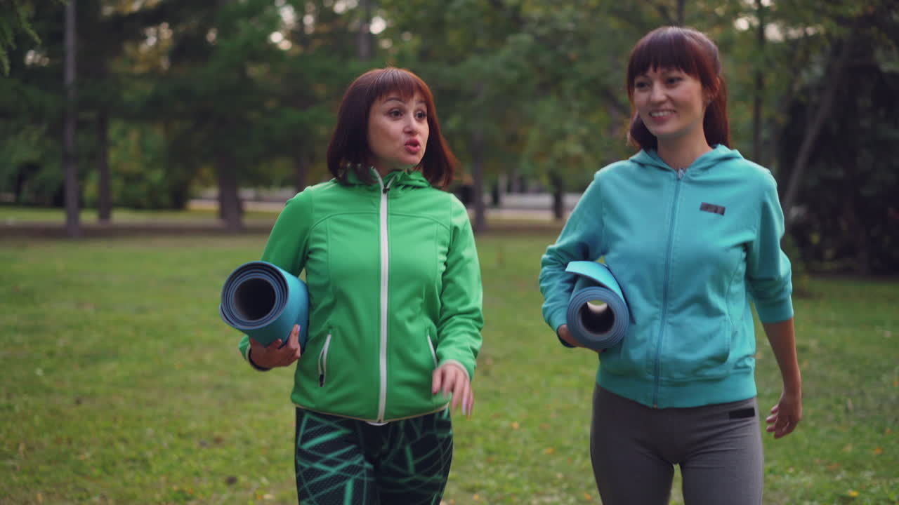 Two Women Walking in a Park with Yoga Mats