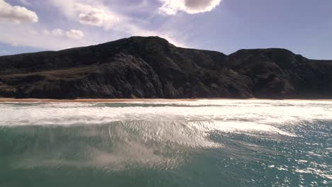 Drone-flying-close-over-ocean-waves-rising-up-to-the-mountains-cliffs-coast-praia-beach-viewpoint-of-castelejo-in-Sagres-Portugal