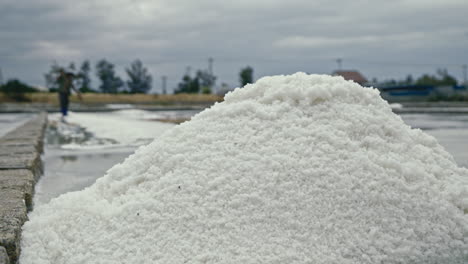 large pile of salt at a salt farm with a worker in the background