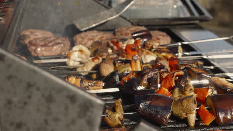 chef flipping hamburgers on bbq with vegetable shish kebabs with flames and smoke