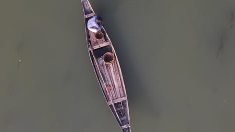 asian fisherman fishing in traditional wooden boat, aerial top down view