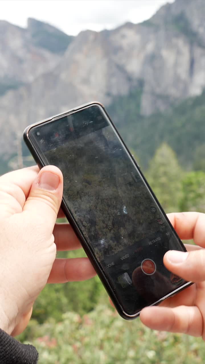 Mani che riprendono con smartphone un paesaggio montano suggestivo