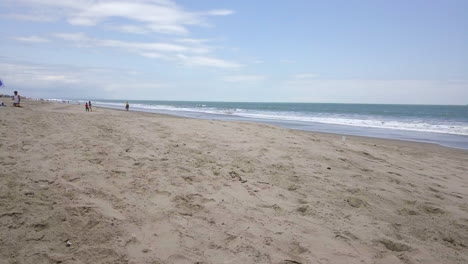 Flying-very-low-with-a-drone-close-or-through-umbrella-and-old-wooden-beach-chairs-with-the-ocean,-beach-and-some-people-in-the-background