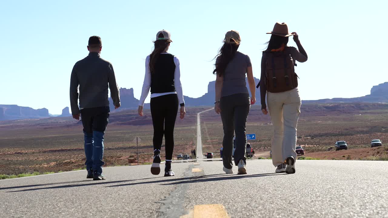 Group of Friends Walking on a Long Road in Monument Valley