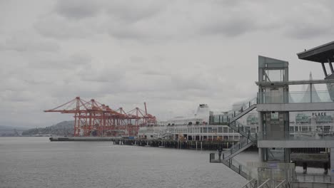 vista del icónico edificio canada place, el puerto de vancouver y las grúas rojas en un día nublado, columbia británica, canadá
