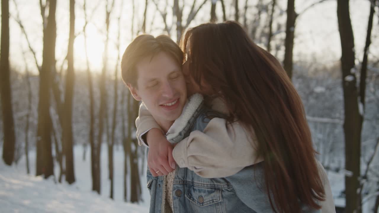feliz joven y hermosa pareja se divierten juntos en el soleado bosque de invierno