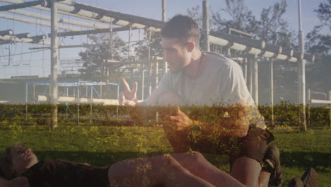coaching athlete on grass field, man with industrial structures in background