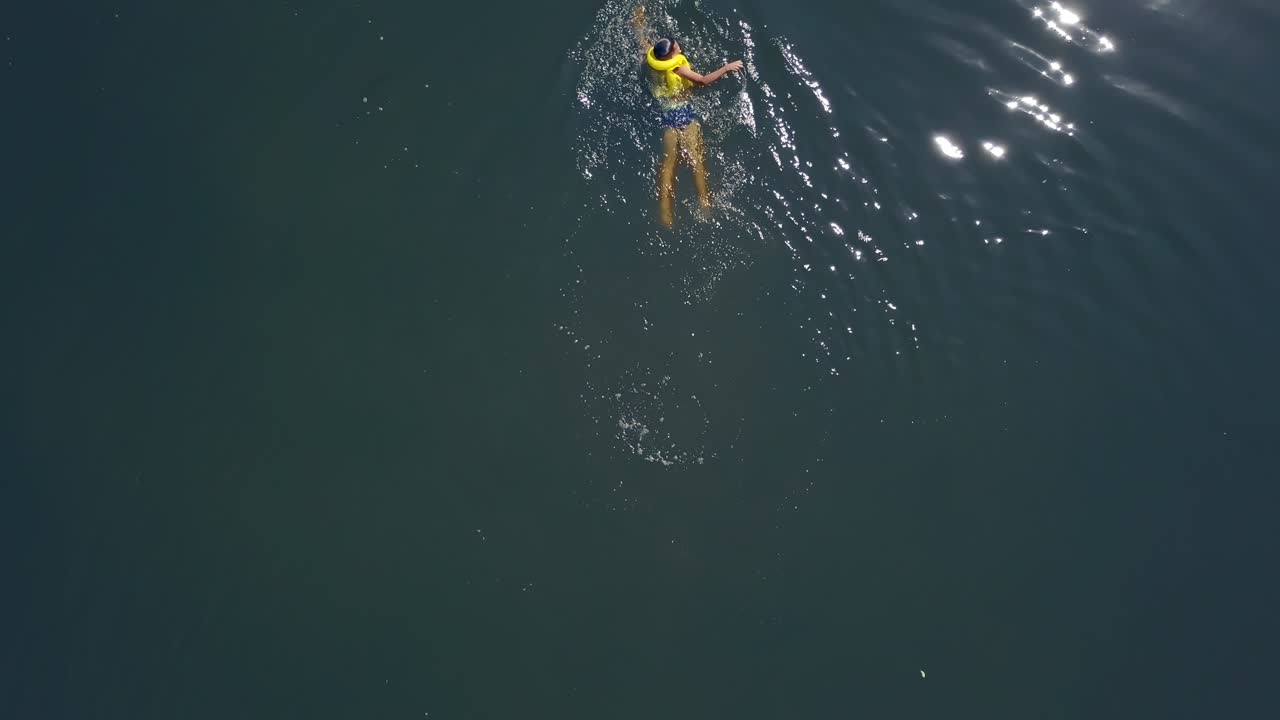Little boy swimming in the lake. Happy children on summer vacation. Aerial view.