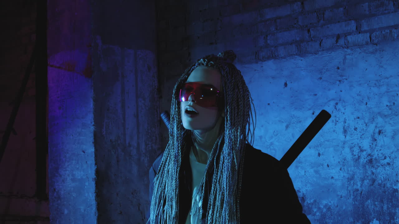 una chica con dreadlocks y katanas está de pie junto a una pared de ladrillo de neón y toma una selfie en un teléfono móvil