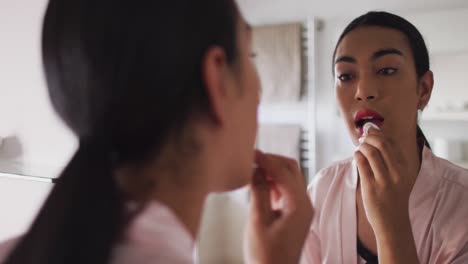 mixed race gender fluid person standing in bathroom and using a lipstick