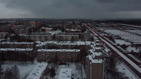 Kaunas-city-street-and-snow-covered-block-apartment-buildings,-aerial-view