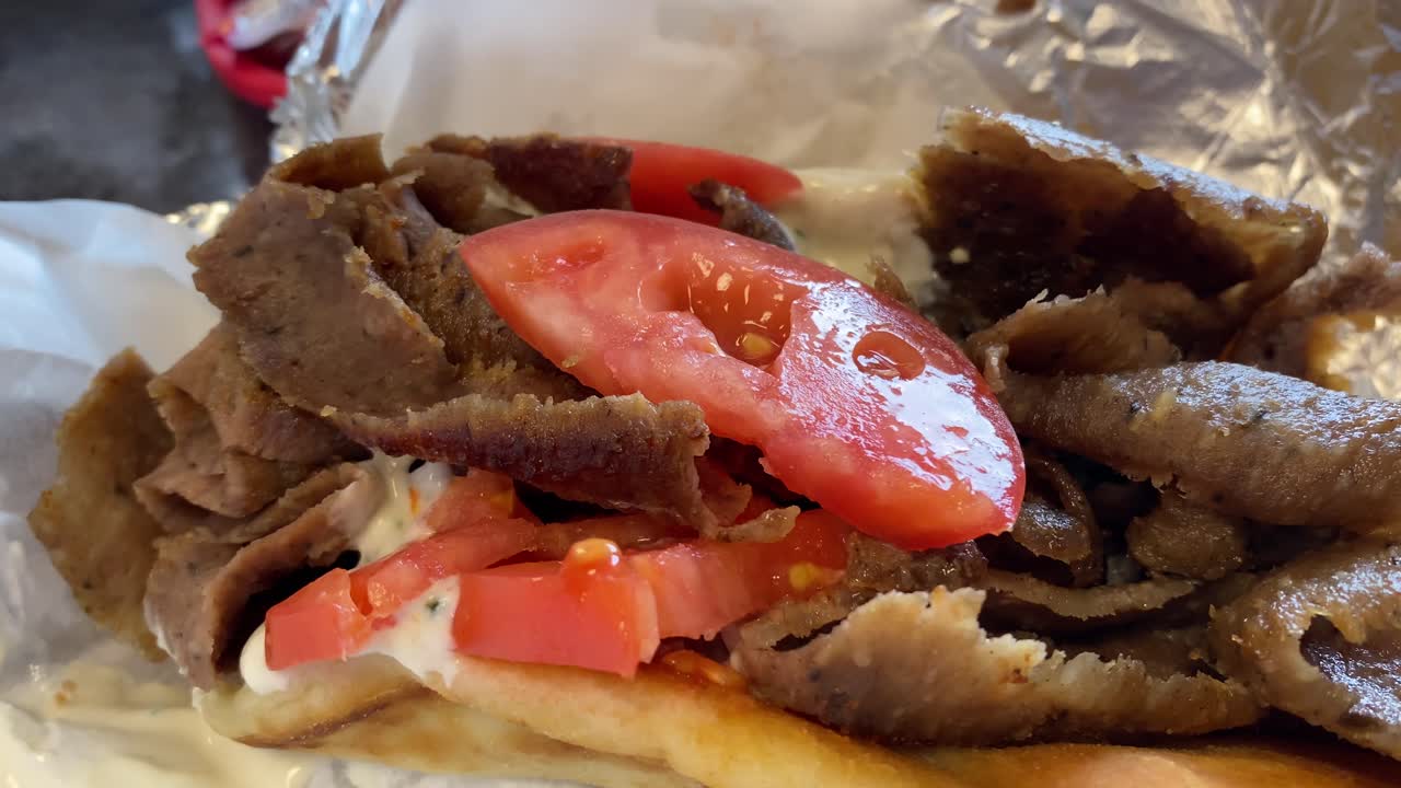cordero giroscópico con rebanadas de tomate servido en un restaurante en fort wayne, indiana con video en primer plano