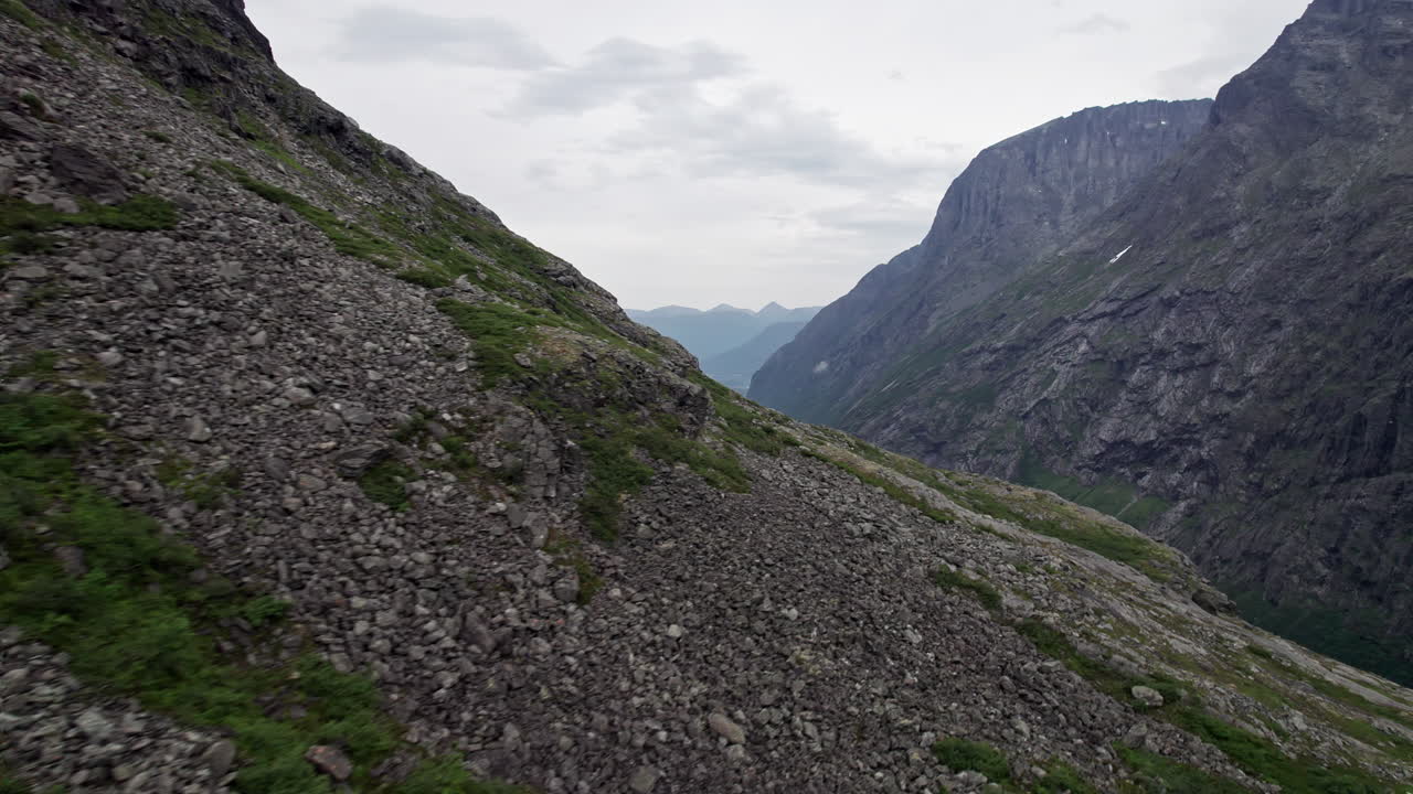 Inquadratura ravvicinata con panoramica su un versante collinare coperto di ghiaione e rocce