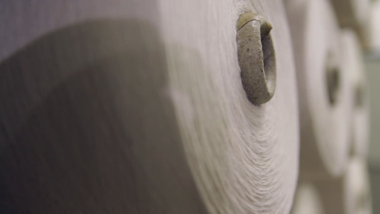 primer plano de hilos de hilar con hilos en un estante en una planta textil