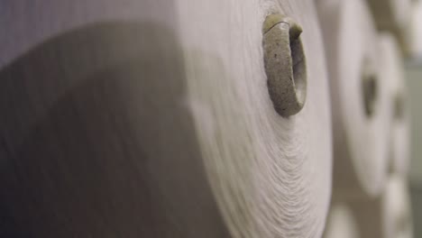 primer plano de hilos de hilar con hilos en un estante en una planta textil