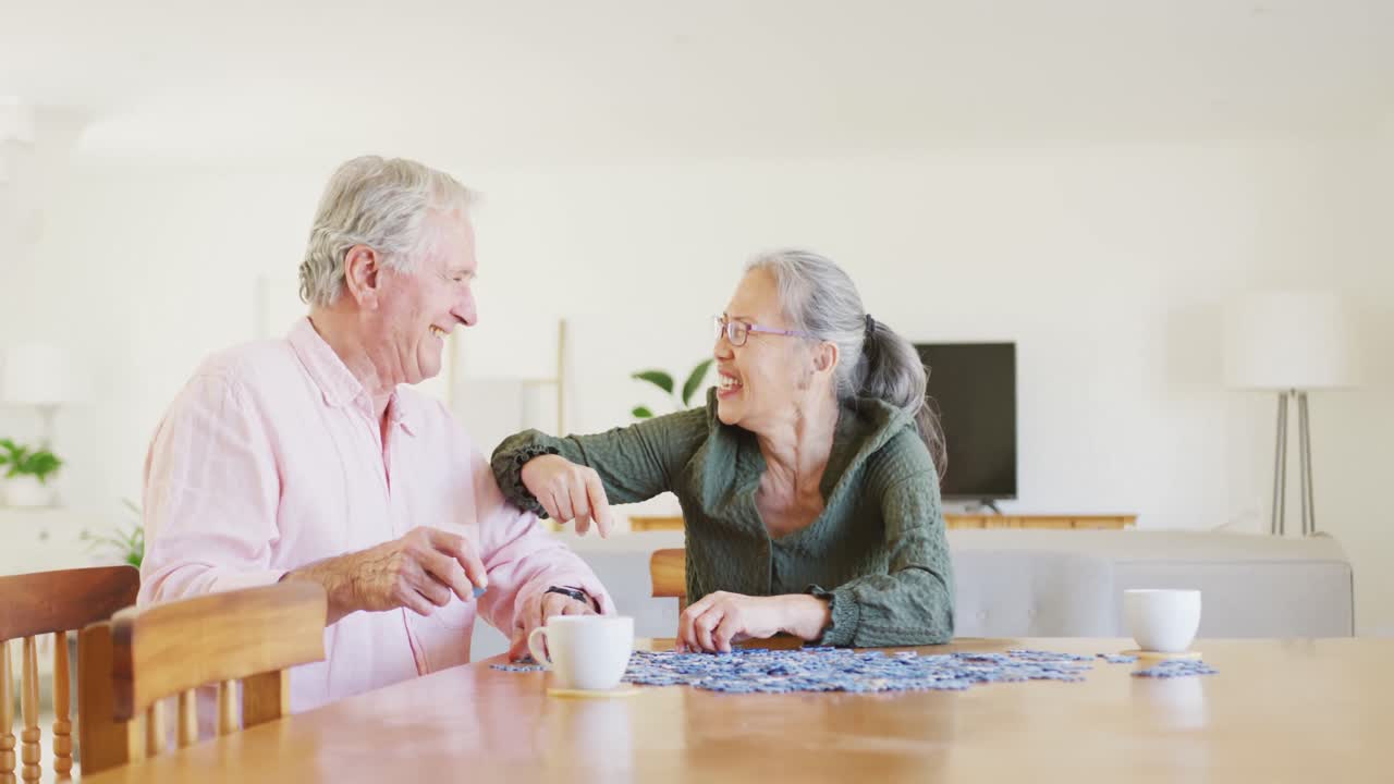 테이블 에 앉아 퍼즐 을 하는 행복 한 고위 부부