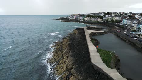 Aerial-shot-of-waves-crashing-against-rocky-coastline,-slow-motion---Bangor,-Northern-Ireland