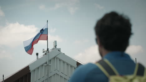 close shot from a hiker in blur looking at the slovenian flag attached at the roof of a mountain cottage on mountain snežnik