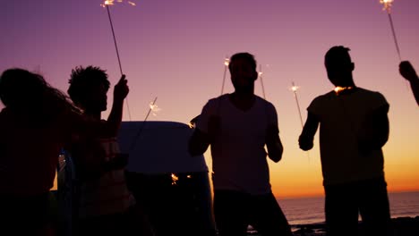 young adult friends having fun on the beach at night with sparklers 4k