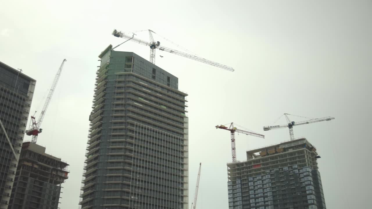Under Construction High-rise Buildings With Industrial Tower Cranes Against The Clear Sky.- panning shot