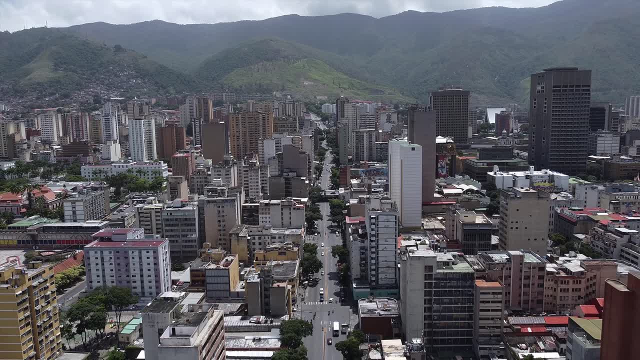 vuelo inverso durante el día sobre la avenida baralt, revelando el centro de caracas y mostrando el horizonte de la ciudad contra la cordillera circundante.