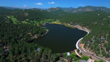 evergreen lake house waterfall dam park and rec center golf course keys on the green downtown mountain town summer sunny blue sky flag water dam colorado aerial drone circle right motion