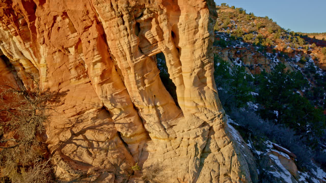 Aerial drone shot capturing a stunning rock arch glowing in the sunrise near Kanab, Utah.