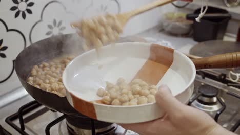 putting out cooked chickpeas from boiling pan into the plate