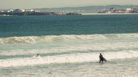 Couple of surfers walking into ocean, back view