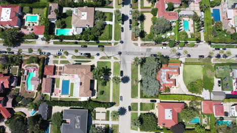 drone zooms out to reveal palm tree lined streets with cars driving, and mansions in west hollywood, california