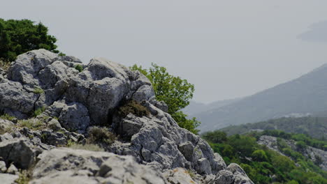 Vista-Satica-Del-Acantilado-De-Granito-Con-Arbustos-Verdes-Con-Vistas-Al-Amplio-Valle-En-Croacia