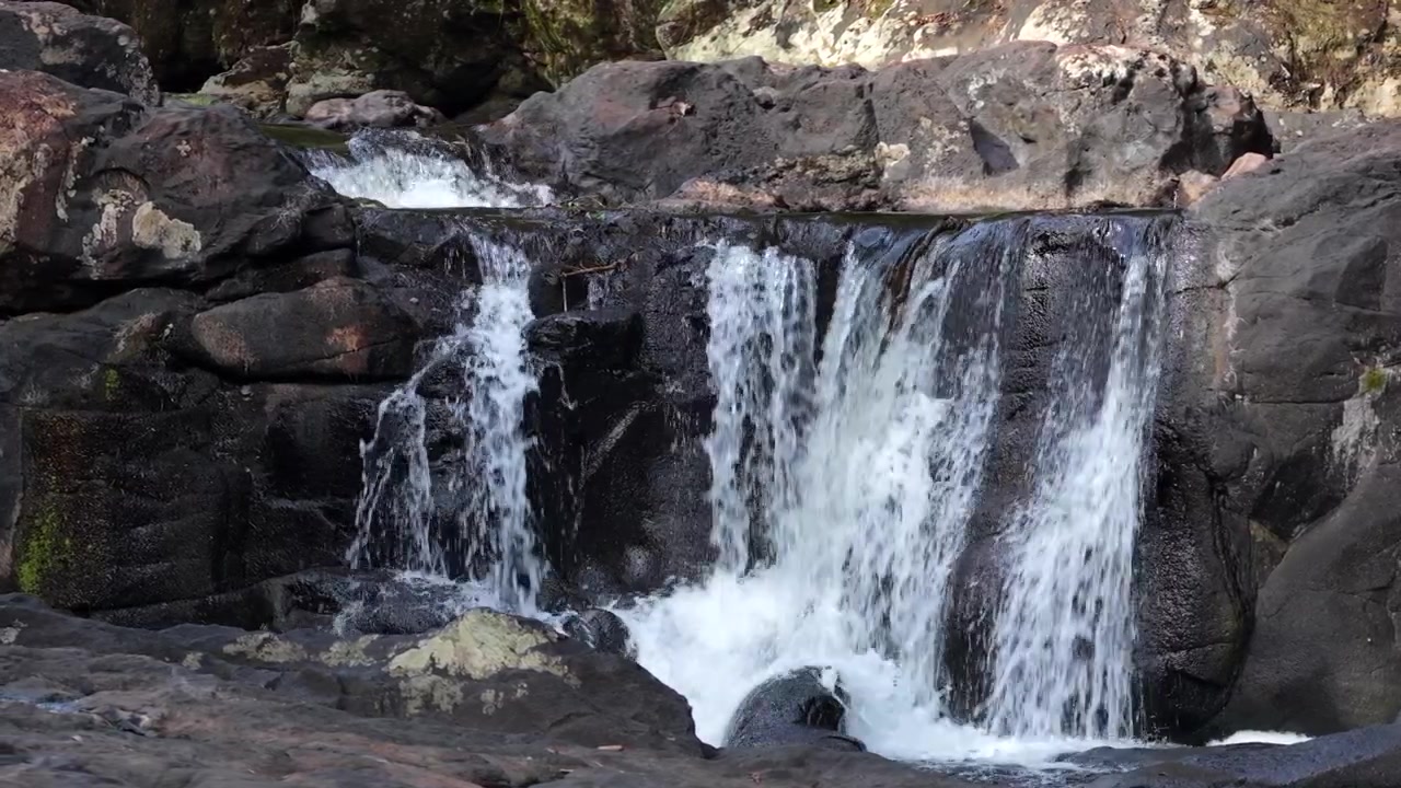 Salto Tres de Mayo, Arjantin, Misiones, Garuhape yakınlarındaki Gruta India'da koyu volkanik kaya üzerinden çağlayarak Parana Ormanı içinde bir dizi küçük şelale oluşturuyor, drone yan kaydırma