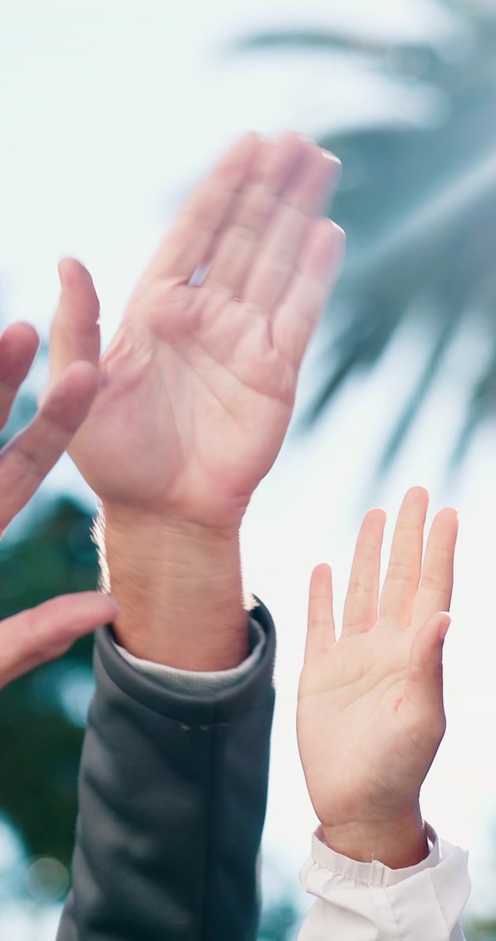 Gruppo eterogeneo di persone che alzano le mani all'aperto