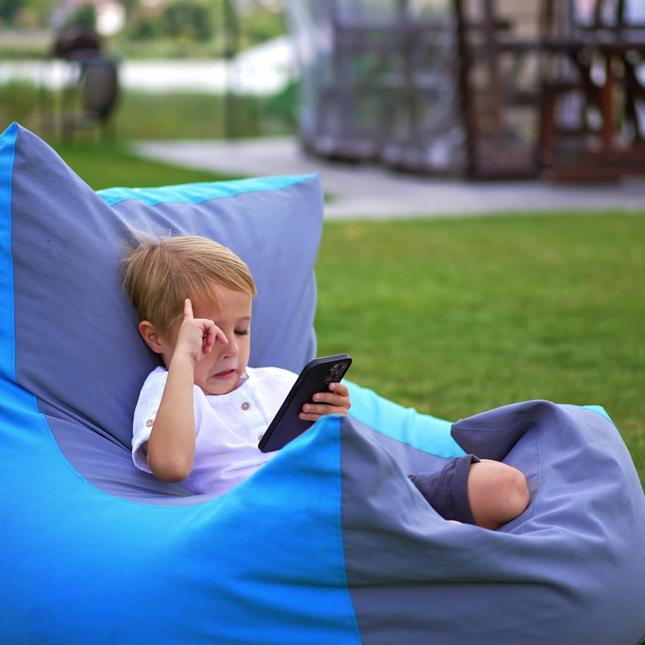Child playing outdoor with phone. Smart young boy with gadget