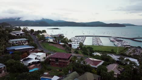 airlie playa bahía laguna mar de coral marina drone aéreo nubes de lluvia oscura amanecer corazón de la gran barrera de arrecifes whitsundays whitehaven muelle yates veleros edificios airbnb hacia arriba movimiento