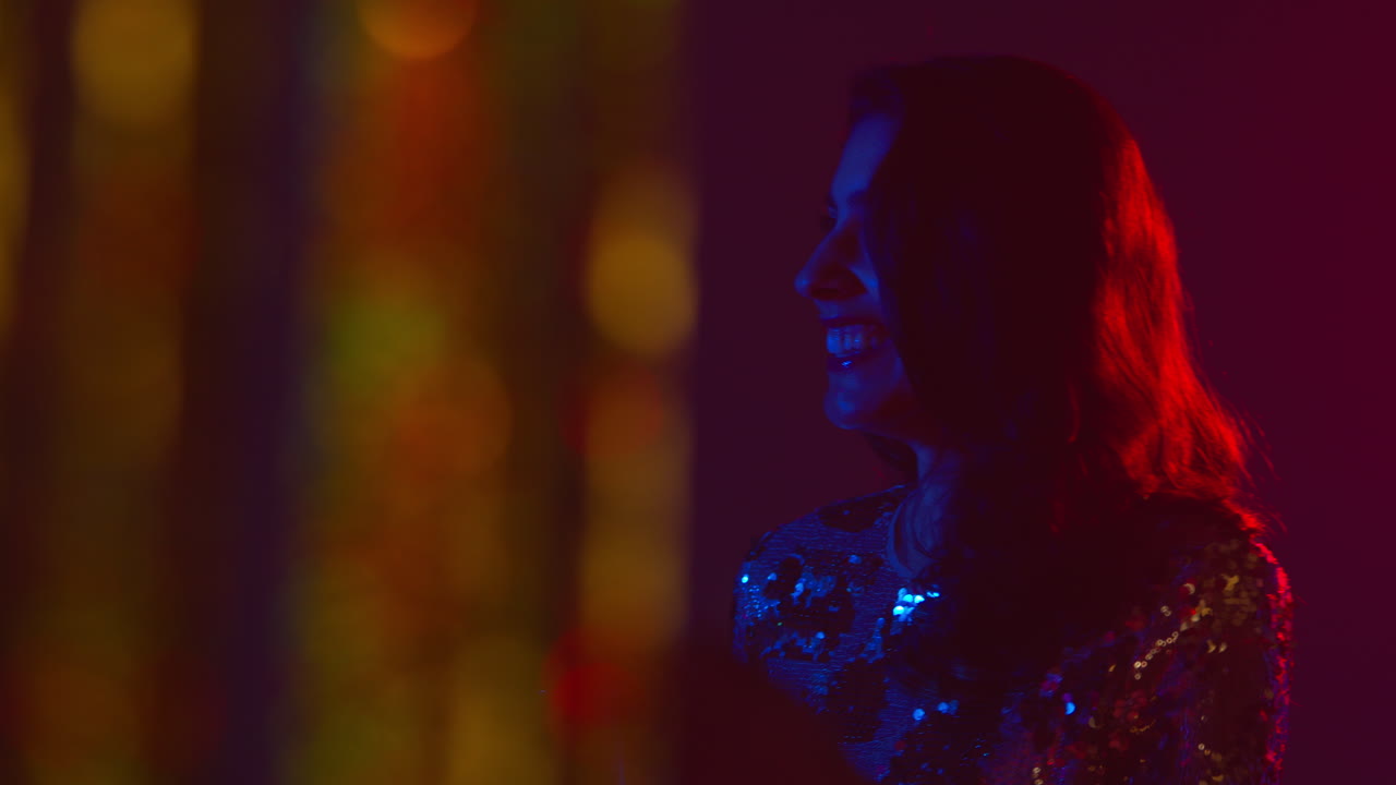 Woman Having Fun In Nightclub Or Bar Shot Through Tinsel Curtain in Foreground