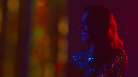 woman having fun in nightclub or bar shot through tinsel curtain in foreground