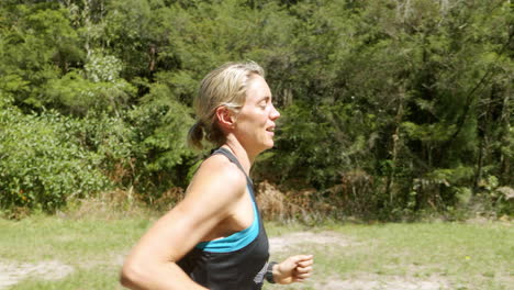 Blonde-Fit-Female-Side-Profile-Running-Through-Green-Park,-4K-Slow-Motion