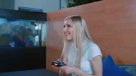 relaxing woman playing console indoors. young casual woman chilling on sofa and playing videogame with gamepad in modern interior