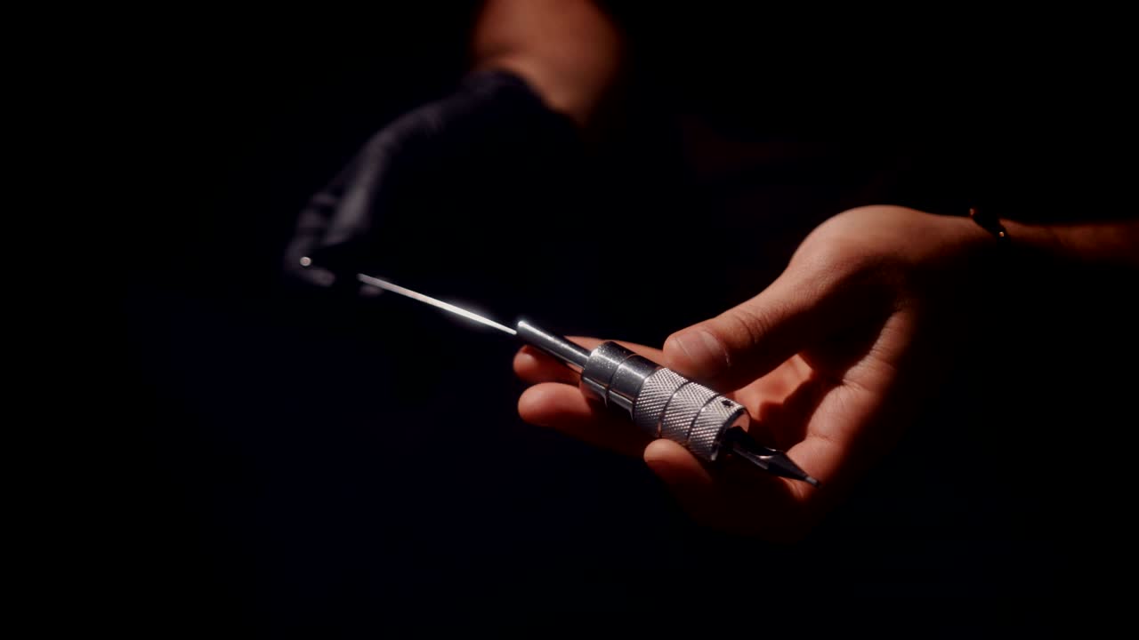 Tattoo artist holding and preparing tattoo machine in studio
