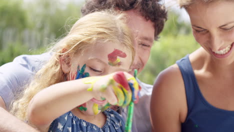 happy family  with little girl painting in the yard creative with mom and dad