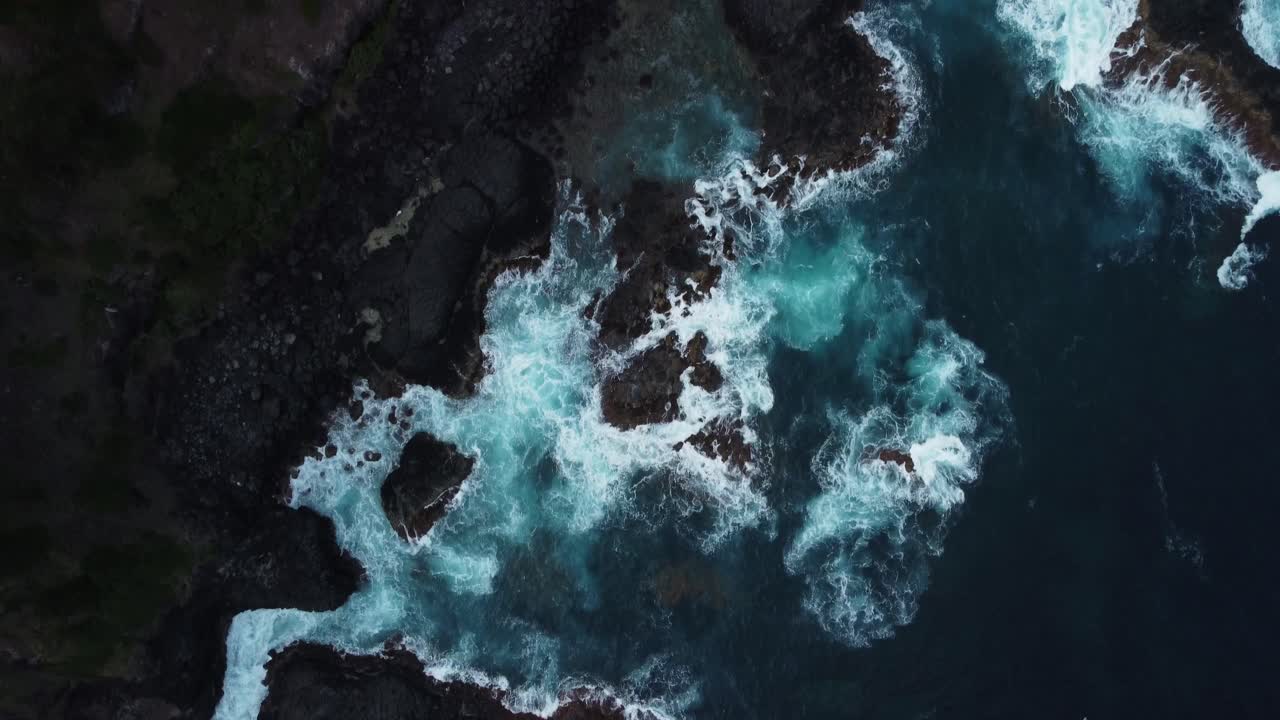 Ripresa aerea in dolly, costa rocciosa invasa da onde oceaniche che si infrangono